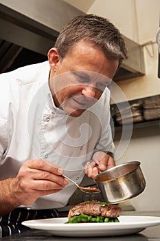 Chef Adding Sauce To Dish In Restaurant