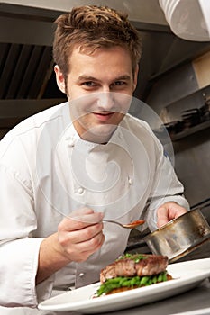 Chef Adding Sauce To Dish In Restaurant Kitchen