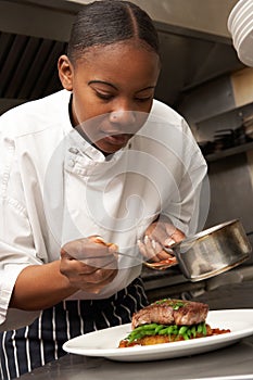 Chef Adding Sauce To Dish In Restaurant Kitchen