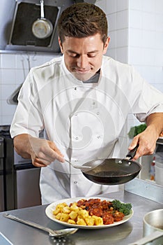 Chef Adding Sauce To Dish In Restaurant Kitchen