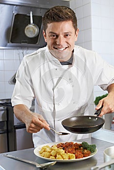 Chef Adding Sauce To Dish In Restaurant Kitchen