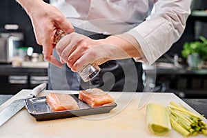 Chef adding spices on fish meat