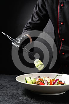 Chef adds cucumber to salad with tweezers