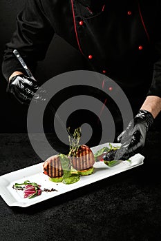 Chef adds thyme to meat on the plate