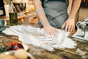 Chef in apron, flour,eggs, pasta machine on table