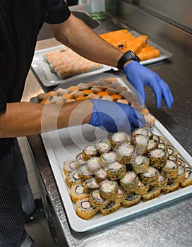 Chef arranging sushi rolls in restaurant kitchen, catering business