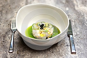 Chef assembles gourmet fish ceviche dish with corn, cucumber in green sauce photo
