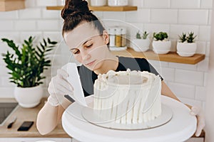 Chef or baker decorating cake with white whipped cream.