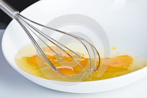 Chef beating eggs in a bowl witha a manual mixer