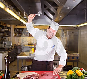 Chef beats meat on the board in restorant kitchen