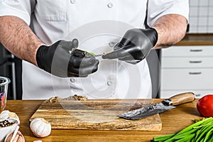 A chef in black gloves prepares guacamole from fresh avacado Hass