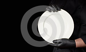 Chef in black uniform  holding a round white empty plate