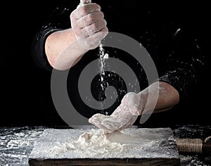 chef in black uniform sifts through his fingers white wheat flour