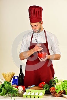 Chef with busy face holds bowl and whisk on white
