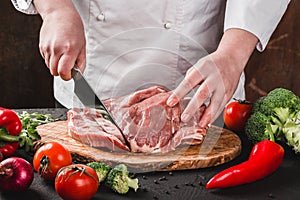 Chef Butcher cutting pork meat with knife on kitchen, cooking food