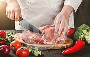 Chef Butcher cutting pork meat with knife on kitchen, cooking food. Toning.