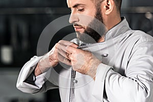 Chef button uniform at kitchen restaurant. Concentrated chef buttoning uniform.