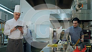 Chef checking up recipes on digital tablet in the professional kitchen