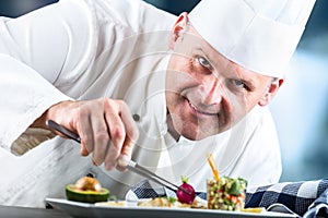 Chef. Chef cooking. Chef decorating dish. Chef preparing a meal. Chef in hotel or restaurant kitchen prepares decorating dish with