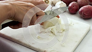 Chef chopping onion on marble cutting board, close up video