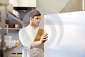 Chef with clipboard doing inventory at kitchen