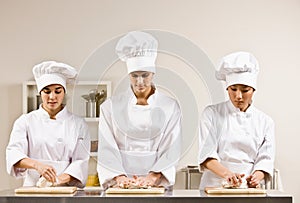 Chef co-workers kneading dough in kitchen