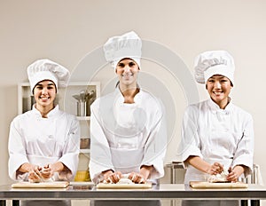Chef co-workers kneading dough in kitchen