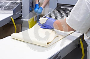 Chef condite rolls puff pastry on a dough sheeter for pizza making, rolling dough