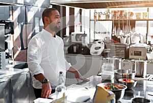 The chef conducts a master class in cooking. On the background is kitchen utensils, on the table in front of him vegetables in