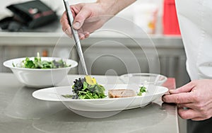 Chef cook finishing salad and pastry dish with pincers and flowers