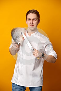 Chef cook holding a big atlantic salmon fish on his shoulder  on yellow background