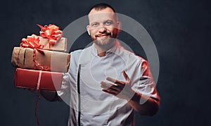 Chef cook holds colorful paper Christmas gifts.