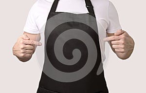 Chef cook pointing on black apron