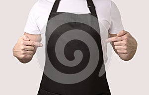 Chef cook pointing on black apron photo