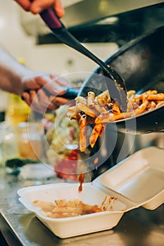 Chef cook pours spaghetti into fast food plastic delivery pack