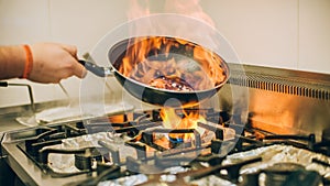 Chef cook prepares meal in flame fire burn frying pan photo