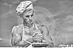 Chef cook preparing dough for baking with flour. Baker concept. Man on busy face wears cooking hat and apron, sky on