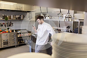 Chef cook with smartphone at restaurant kitchen