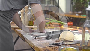 Chef cook sprinkling flour on pizza dough while rolling with roller pin. Man making dough for fresh pasta in italian