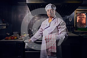 Chef cook in a white apron and cooks hat on a kitchen