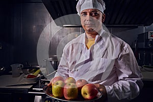 Chef cook in a white apron and cooks hat on a kitchen