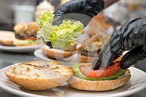 Chef cooking burger,close-up, making sandwich, fast food concept, recipe of preparing homemade hamburger with vegetables