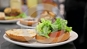 Chef cooking burger, putting meat chop on lettuce close-up, making sandwich, fast food concept, recipe of preparing