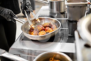 chef cooking chicken wings in on pan in the kitchen