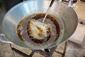 Chef cooking deep-fried fish in the big pan to Chinese banquet food preparation.