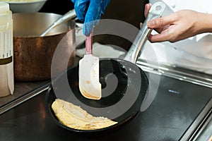 Chef cooking egg omelet in the pan at restaurant.