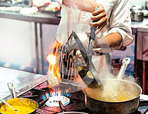 Chef cooking with flame in a frying pan on a kitchen stove