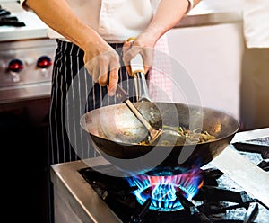 Chef cooking with flame in a frying pan on a kitchen stove