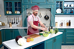 Chef cooking at kitchen. Man on kitchen cooking fresh vegetarian breakfast. Guy prepares salad with green vegetables.