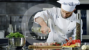 Chef cooking meat at professional kitchen. Portrait of chef cooking raw steak.